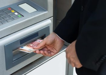 Pessoa a verificar o talão do multibanco após receber dinheiro a menos numa operação de levantamento.