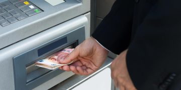 Pessoa a verificar o talão do multibanco após receber dinheiro a menos numa operação de levantamento.