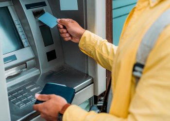 Cartão bancário preso na ranhura de um Multibanco com aviso de possível burla.