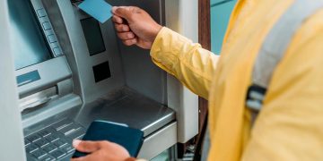 Cartão bancário preso na ranhura de um Multibanco com aviso de possível burla.