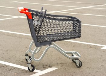 Carrinho de supermercado a ser devolvido ao local correto num parque de estacionamento