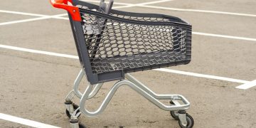 Carrinho de supermercado a ser devolvido ao local correto num parque de estacionamento