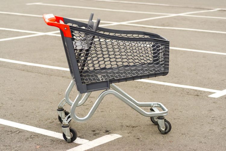 Carrinho de supermercado a ser devolvido ao local correto num parque de estacionamento