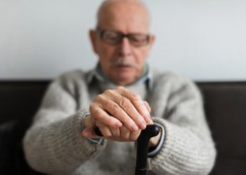 Idoso preocupado a olhar para telemóvel após fraude por SMS