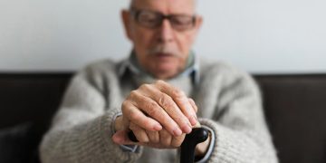 Idoso preocupado a olhar para telemóvel após fraude por SMS