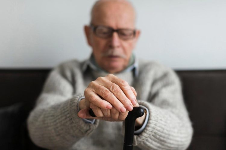 Idoso preocupado a olhar para telemóvel após fraude por SMS