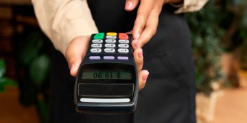 Utilizador a tapar o teclado de um terminal Multibanco ao introduzir o PIN