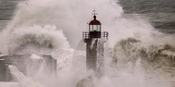 ondas gigantes a bater na costa portuguesa durante tempestade com céu escuro