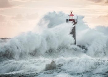 Ondas gigantes a bater na costa portuguesa sob céu escuro e vento forte