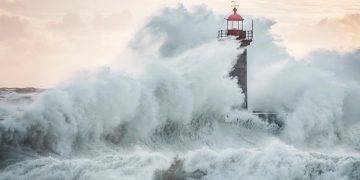 Ondas gigantes a bater na costa portuguesa sob céu escuro e vento forte