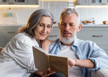 casal sénior feliz a caminhar na praia ao pôr do sol simbolizando reforma antecipada