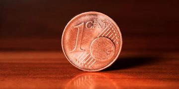 Moedas de 1 e 2 cêntimos espalhadas sobre mesa com carteira aberta e trocos acumulados